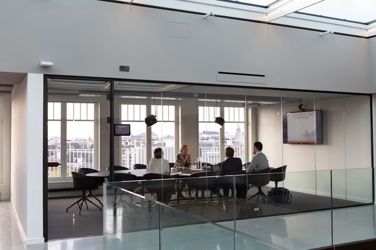 Equipo reunido en una sala de cristal de una oficina luminosa